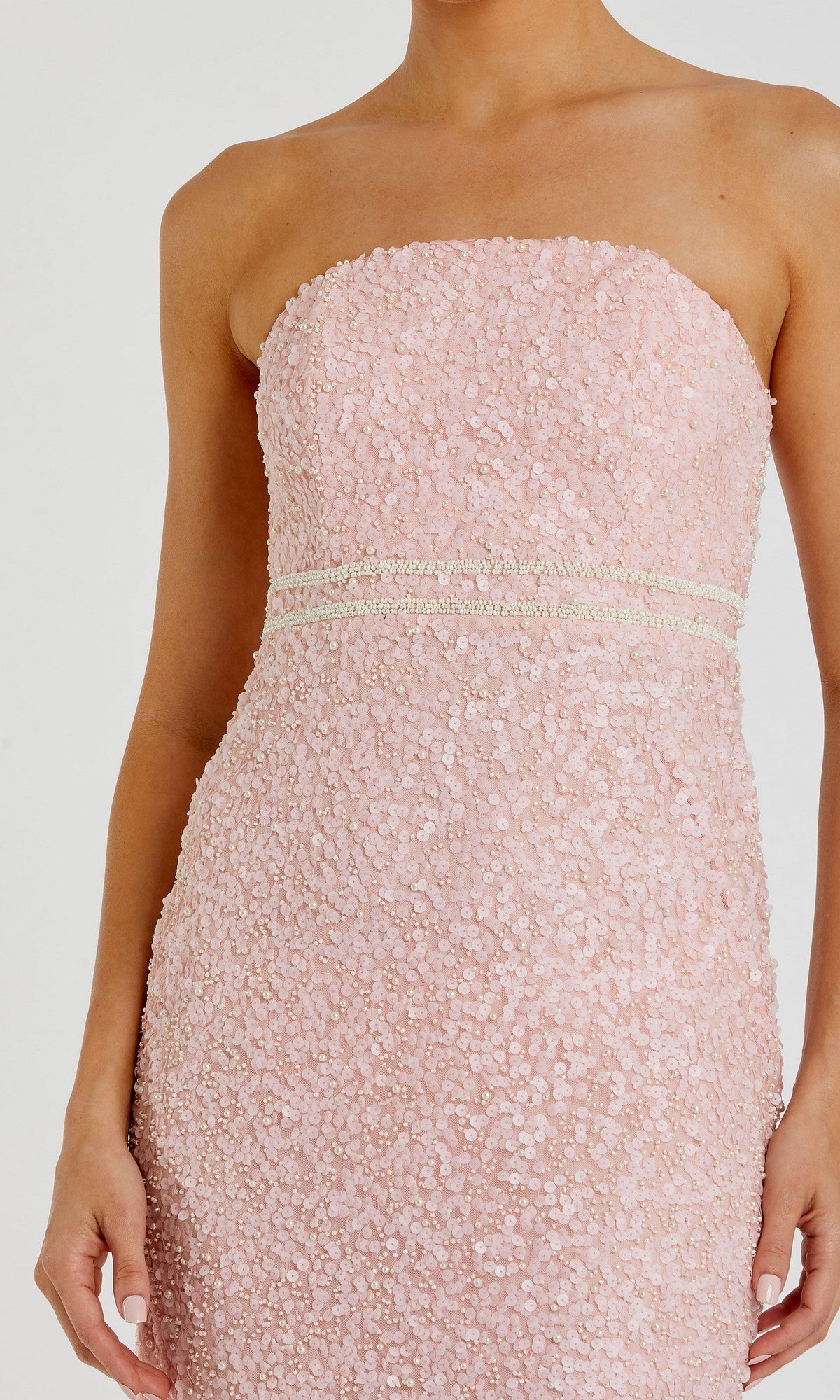 A woman wearing the Tea-Length Party Dress: Mac Duggal 94200—a fitted, strapless light pink dress adorned with pearls, textured sequin detailing, and two horizontal decorative bands at the waist.